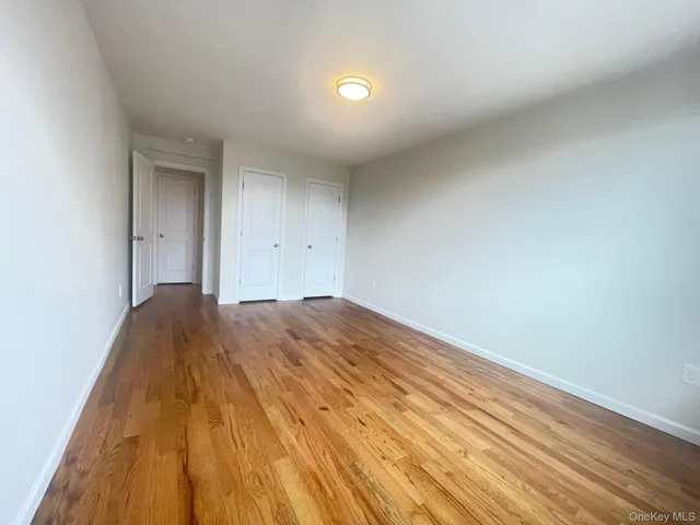 a view of an empty room with wooden floor and closet