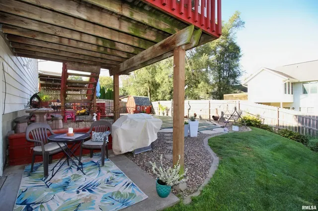 a view of a patio with table and chairs potted plants and floor to ceiling window