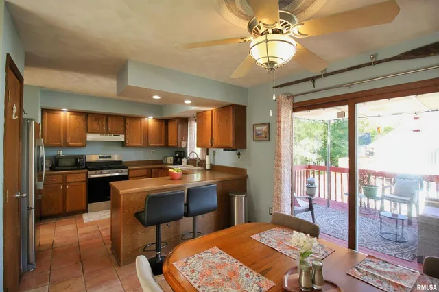 a kitchen with stainless steel appliances granite countertop a stove a refrigerator a kitchen island a table and chairs in it