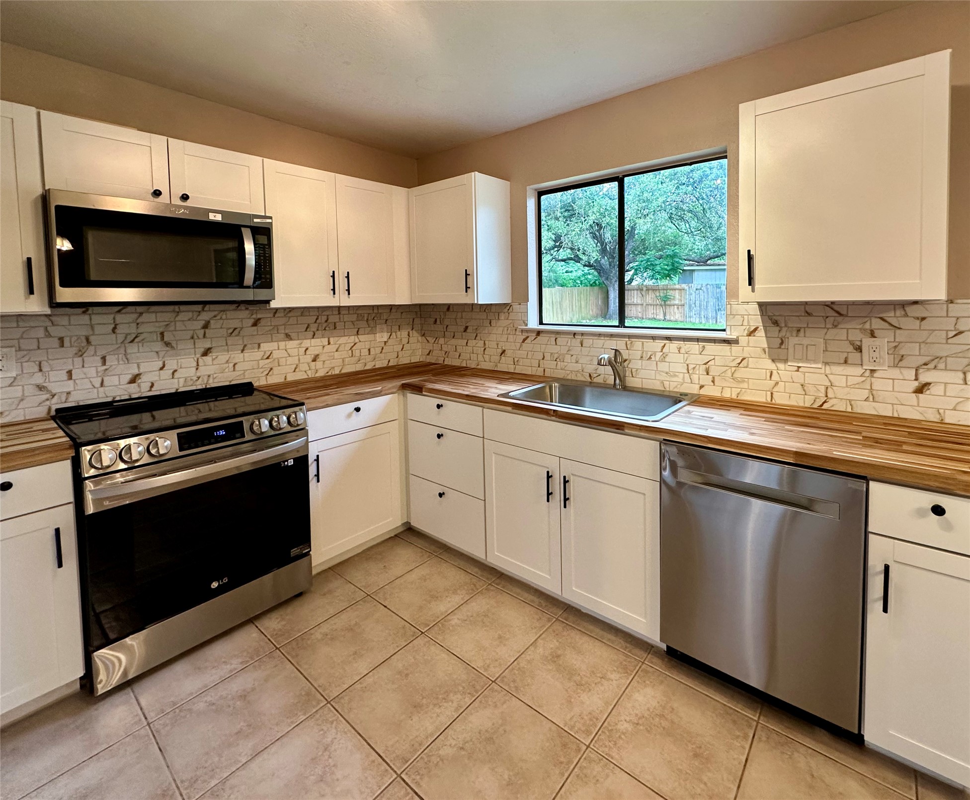 709 Brookside Pass Cedar Park, TX 78613 - Photo 6 of 10 The kitchen features white cabinetry, wood-look countertops, and a tiled backsplash