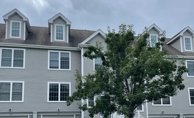 a front view of a house with a tree