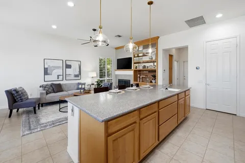 a kitchen with kitchen island granite countertop a stove a sink a oven and a refrigerator