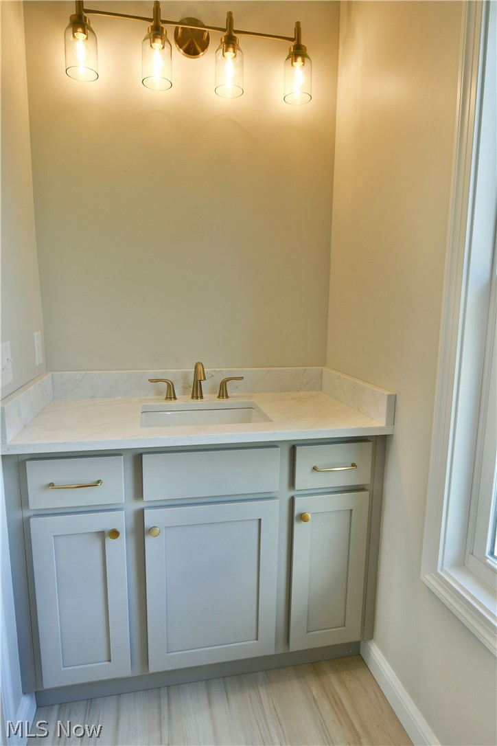 4780 State Rte 5 Cortland, OH 44410 - Photo 28 of 50 Bathroom vanity featuring a light gray cabinet with gold-tone hardware, an undermount sink, and a countertop with an integrated backsplash