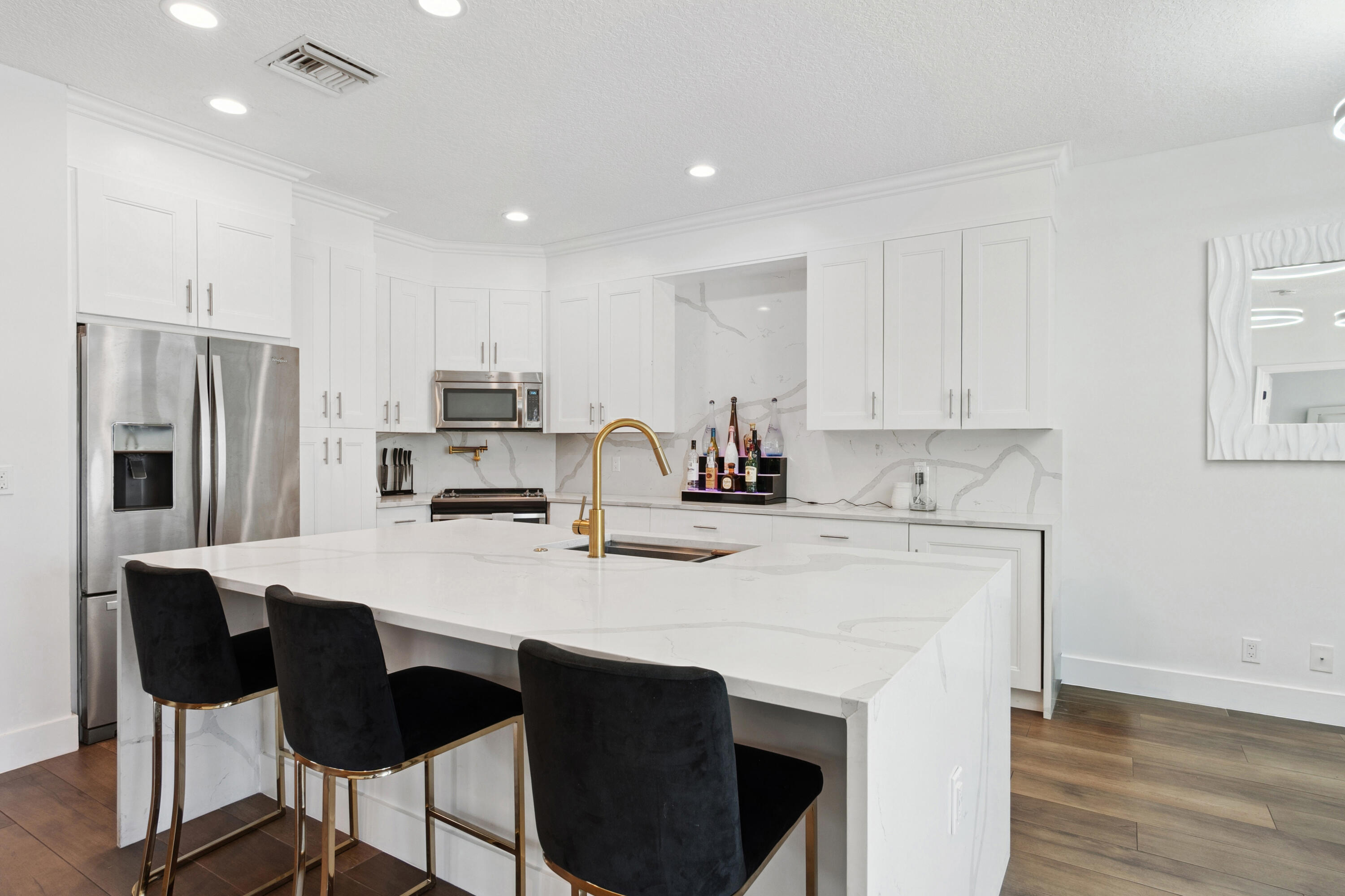 7110 Northwest Turtle Walk Boca Raton, FL 33487 - Photo 6 of 36 a kitchen with a sink a stove a refrigerator and white cabinets with wooden floor