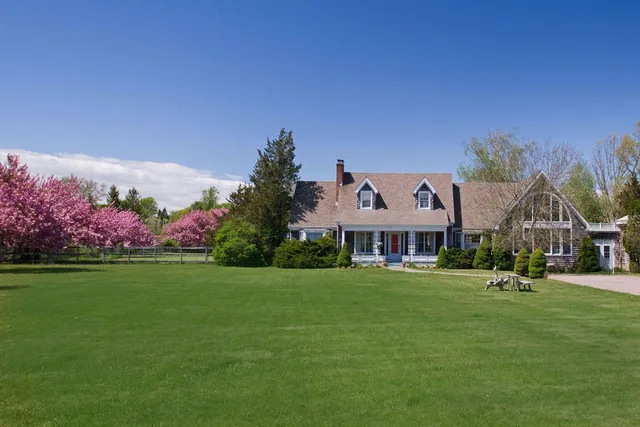 a front view of a house with a garden and trees