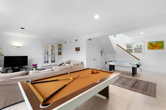 a view of a dining room and livingroom with furniture wooden floor a rug a painting and a clock