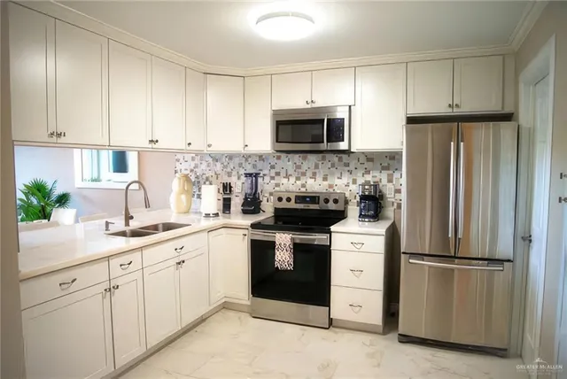 a kitchen with white cabinets sink and stainless steel appliances