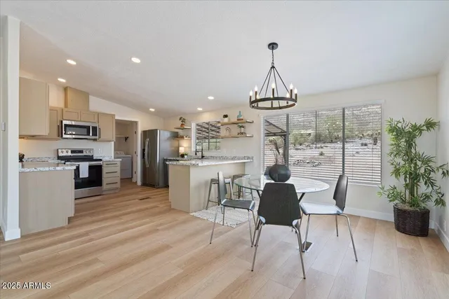 a dining room filled chandelier and kitchen view