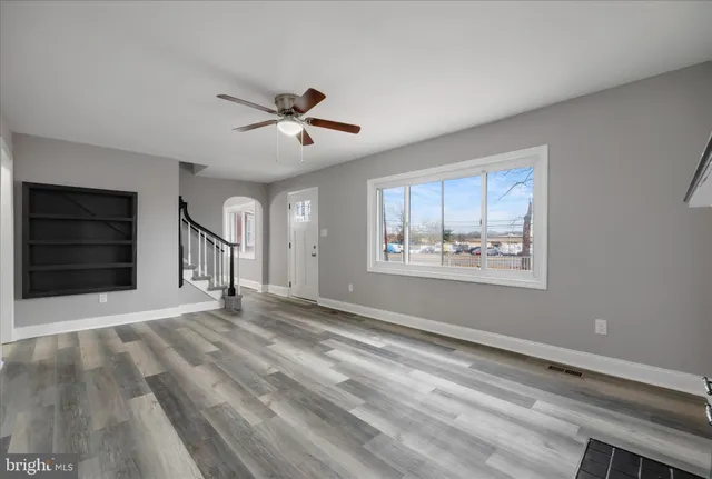 a view of a hallway with wooden floor and a bathroom