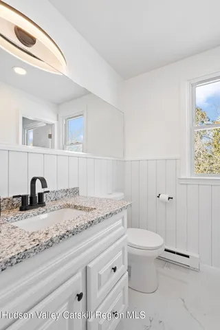 a bathroom with a granite countertop sink and a toilet