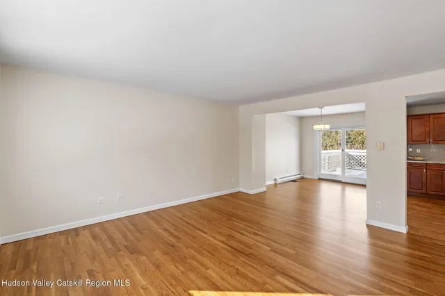 a view of empty room with wooden floor and kitchen view
