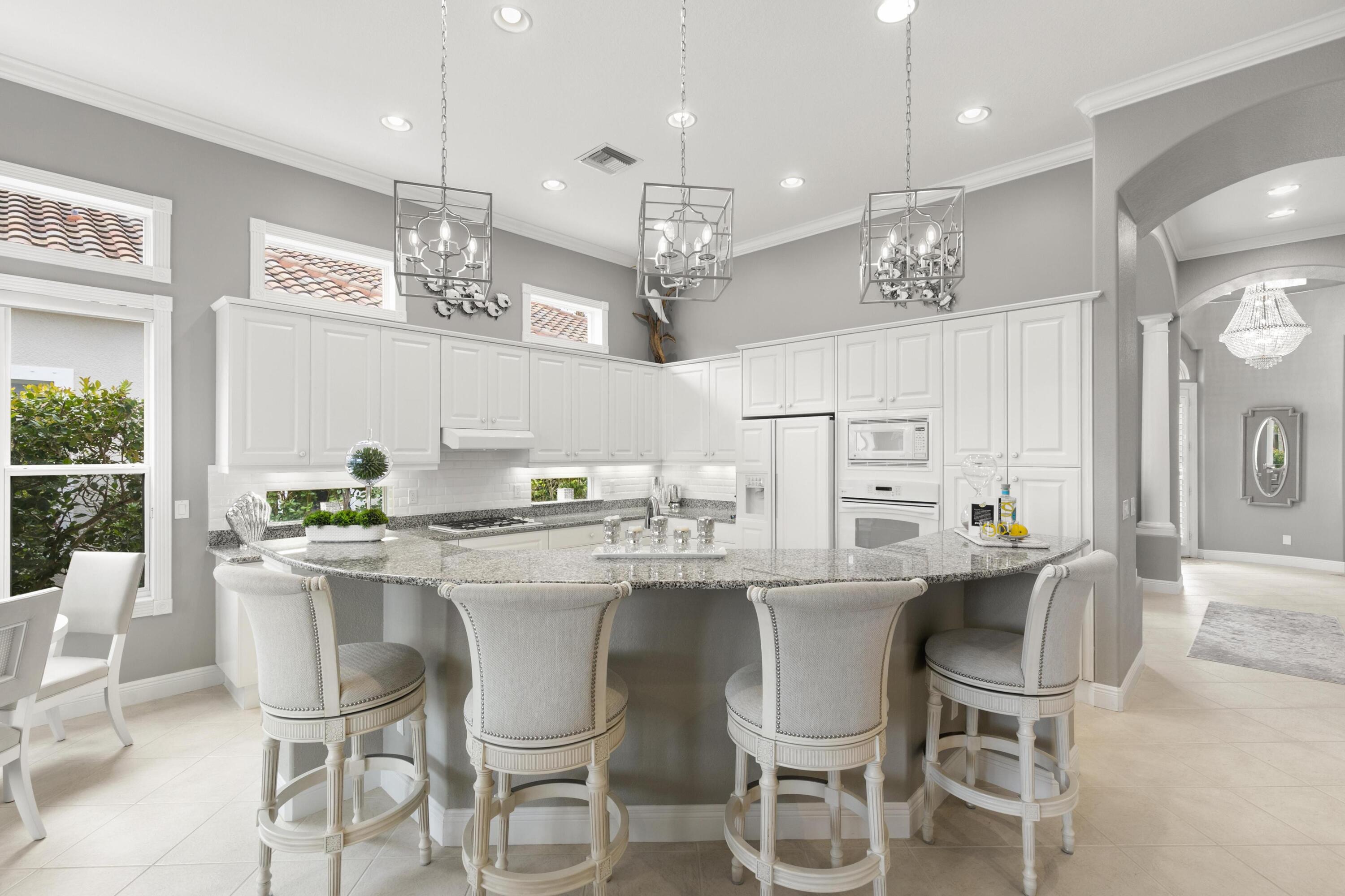 9100 Cherry Oaks Trail Naples, FL 34114 - Photo 9 of 33 a white kitchen with a dining table chairs and white cabinets