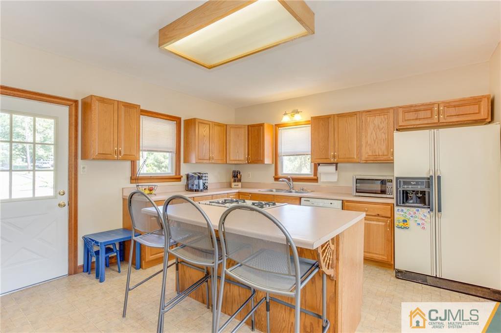 659 Ridge Road Monmouth Junction, NJ 08852 - Photo 8 of 24 a kitchen with a table chairs refrigerator and cabinets