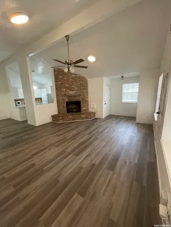 an empty room with wooden floor fireplace and windows