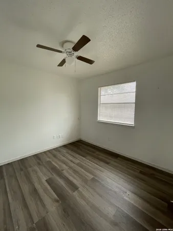 an empty room with wooden floor cabinet and windows