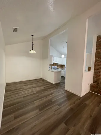 a view of kitchen and empty room with wooden floor