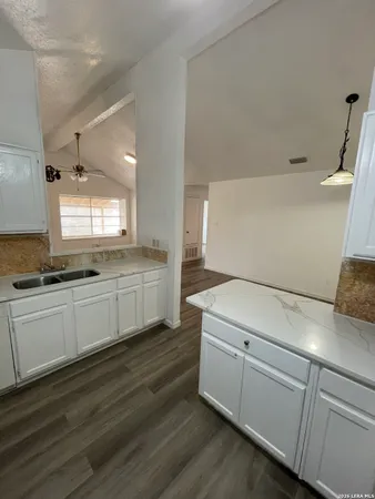 a kitchen with granite countertop white cabinets and white appliances