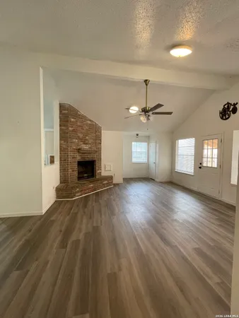 an empty room with wooden floor fireplace and windows