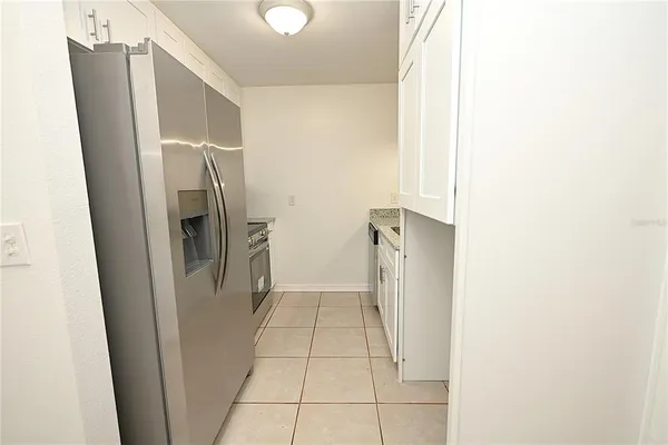 a view of a refrigerator in kitchen and an empty room