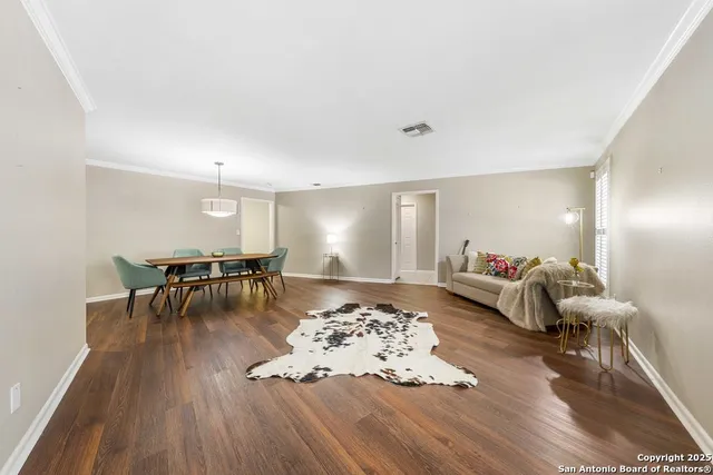 a living room with furniture and a dining table with wooden floor