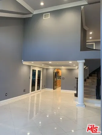 a view of an empty room with kitchen and window