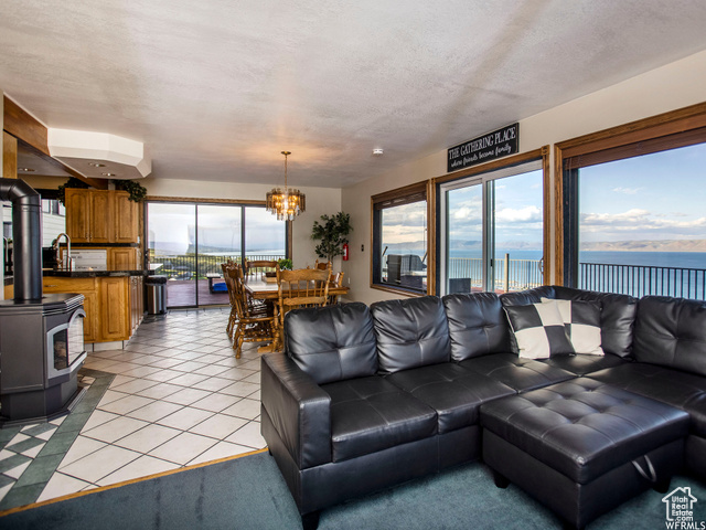 588 Raspberry Patch Road Garden City, UT 84028 - Photo 22 of 74 Living area with a water view, a wood stove, light tile patterned floors, a chandelier, and a textured ceiling