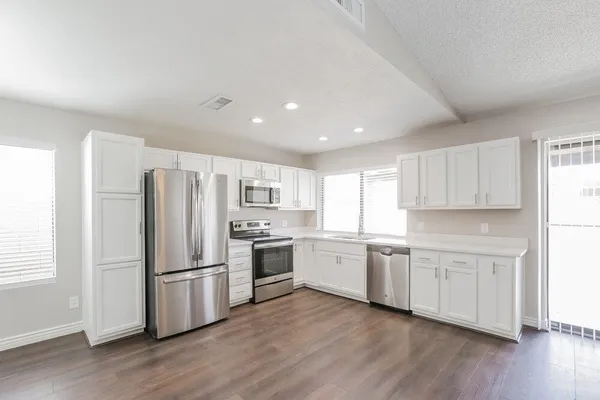 a kitchen with white cabinets stainless steel appliances and wooden floor