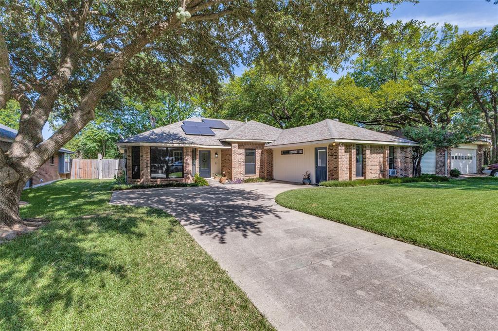 3010 Rambling Drive Dallas, TX 75228 - Photo 2 of 25 Brick veneer exterior with a concrete driveway, mature trees, and solar panels