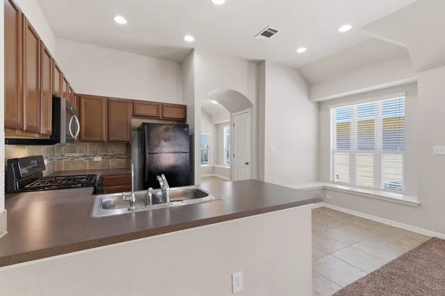 a kitchen with stainless steel appliances granite countertop a sink a stove and a refrigerator with wooden floor