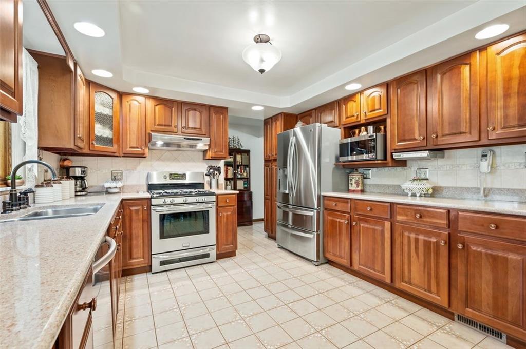 236 Philander Street Pittsburgh, PA 15218 - Photo 12 of 35 a kitchen with stainless steel appliances granite countertop a stove top oven a sink dishwasher a refrigerator and cabinets with wooden floor