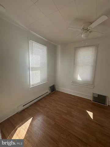 an empty room with wooden floor cabinet and windows