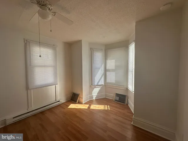 a view of empty room with wooden floor and fan