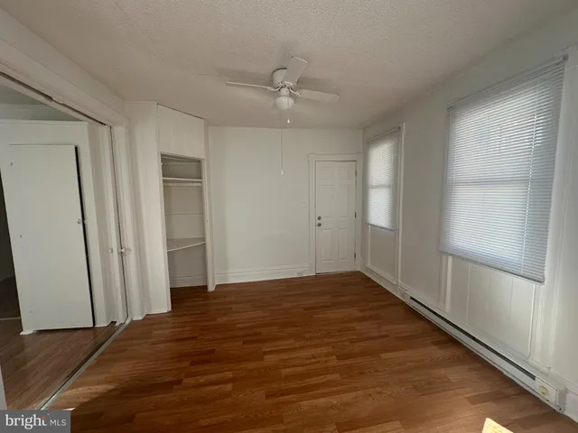 an empty room with wooden floor and a ceiling fan