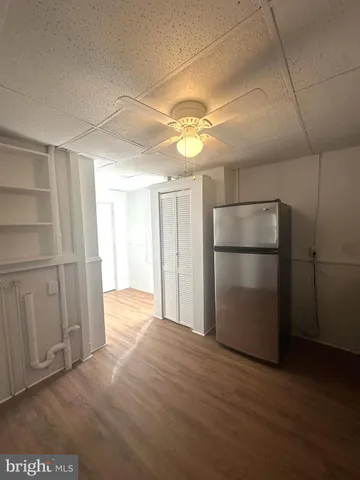 an empty room with wooden floor cabinet and windows