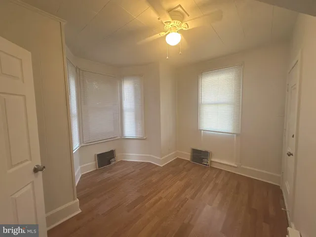 a view of empty room with wooden floor and fan