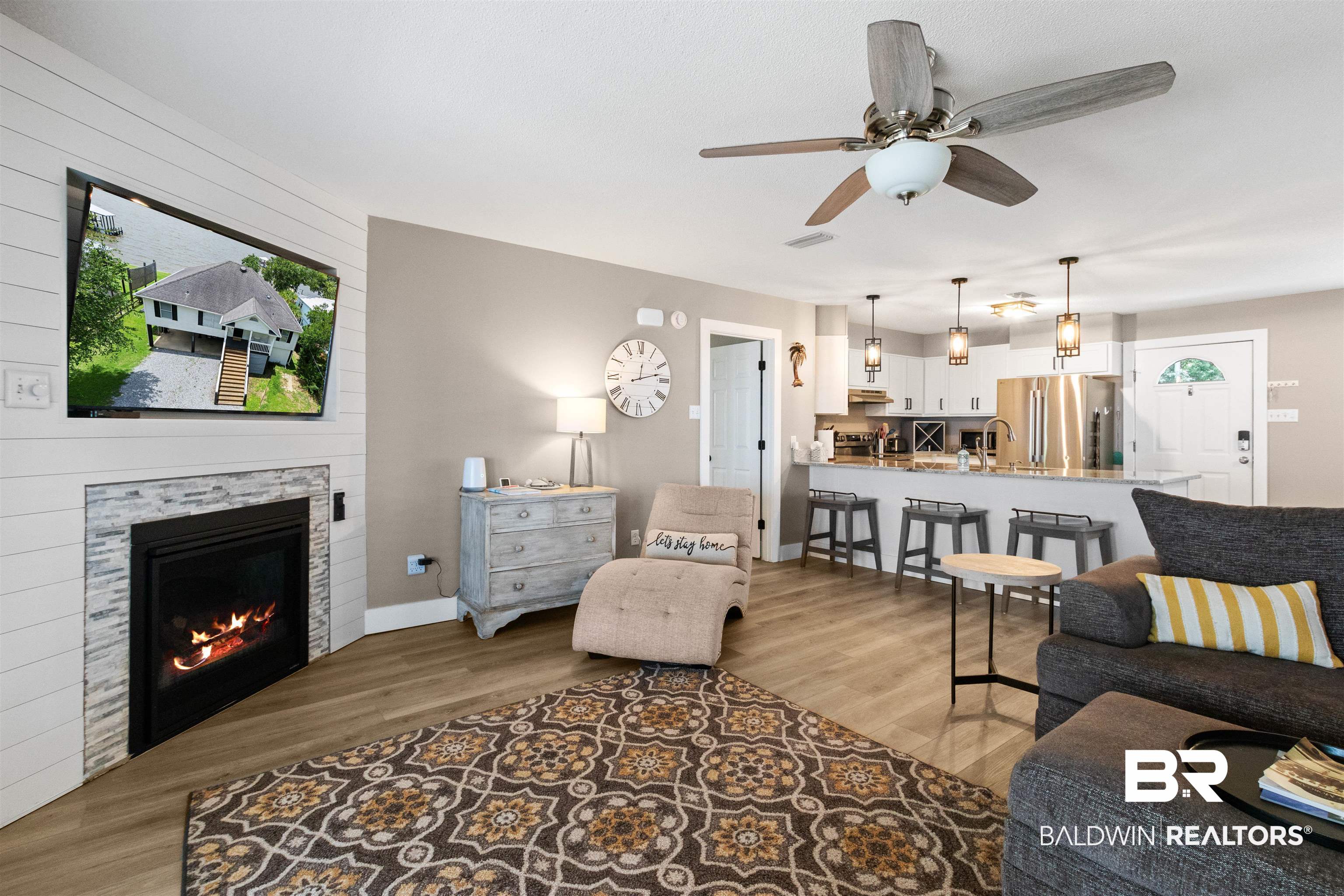 9581 South Bay Street Foley, AL 36535 - Photo 14 of 44 Open-concept living area featuring wood-finish flooring, a contemporary fireplace with stacked stone surround, and shiplap accents