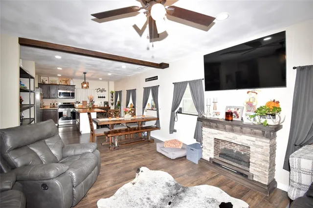 a kitchen with stainless steel appliances kitchen island granite countertop a refrigerator a stove a sink a dining table and chairs with wooden floor