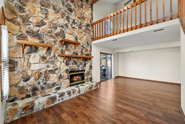 a view of an empty room with wooden floor fireplace and a window