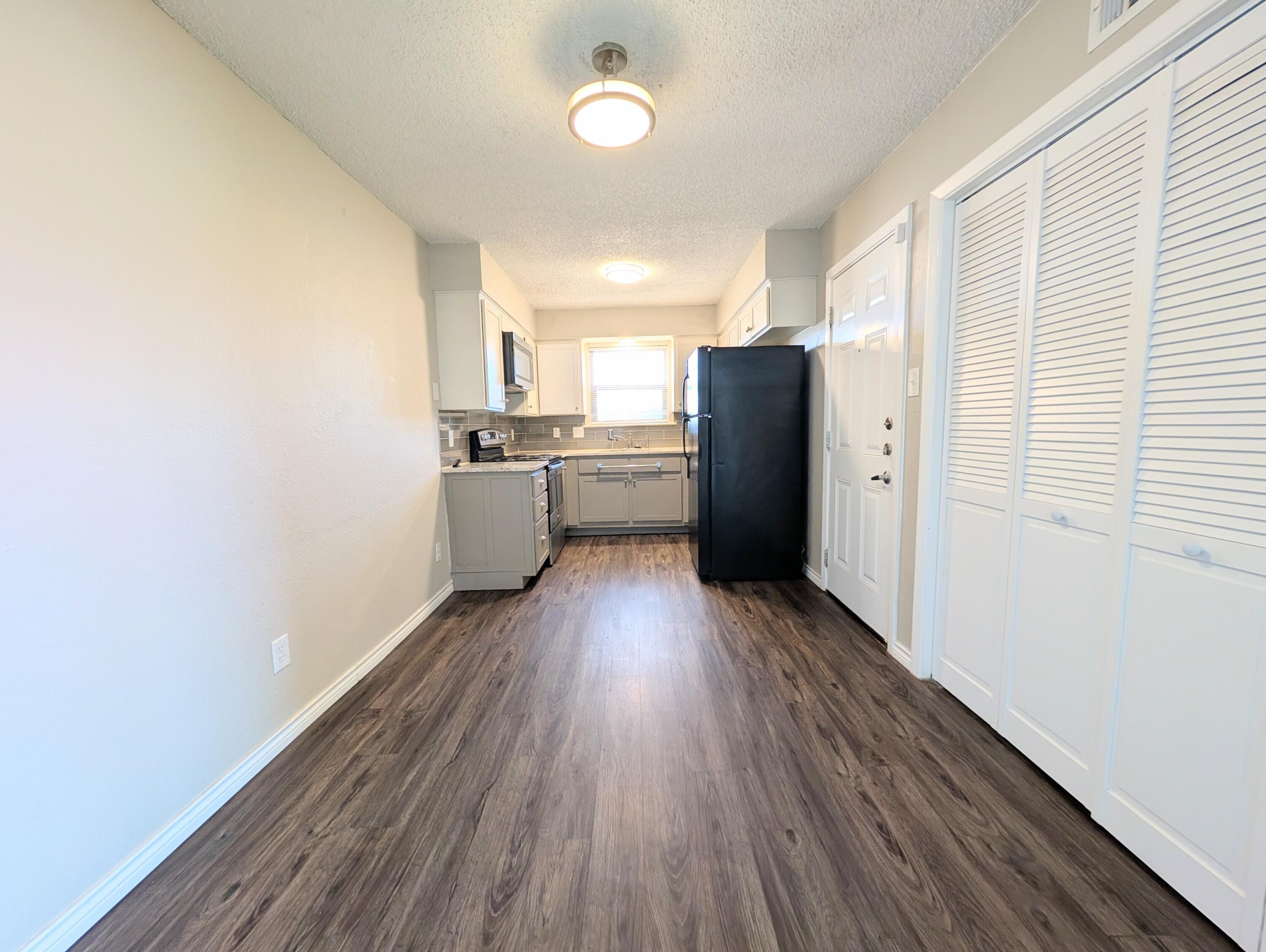 5201 18th Street, Unit A Lubbock, TX 79416 - Photo 3 of 10 a kitchen with wooden floors and refrigerator
