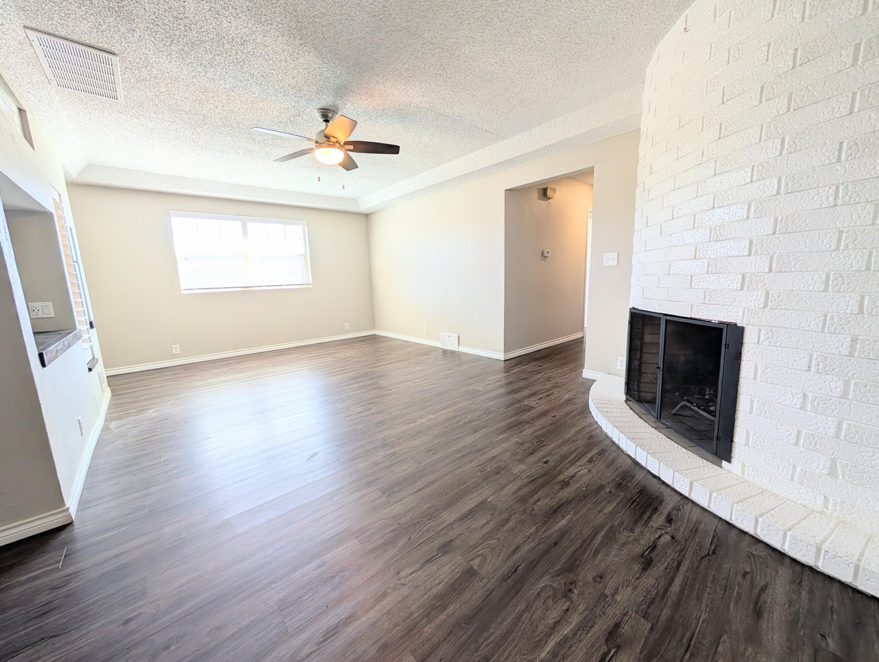 5201 18th Street, Unit A Lubbock, TX 79416 - Photo 4 of 10 an empty room with wooden floor fireplace and windows
