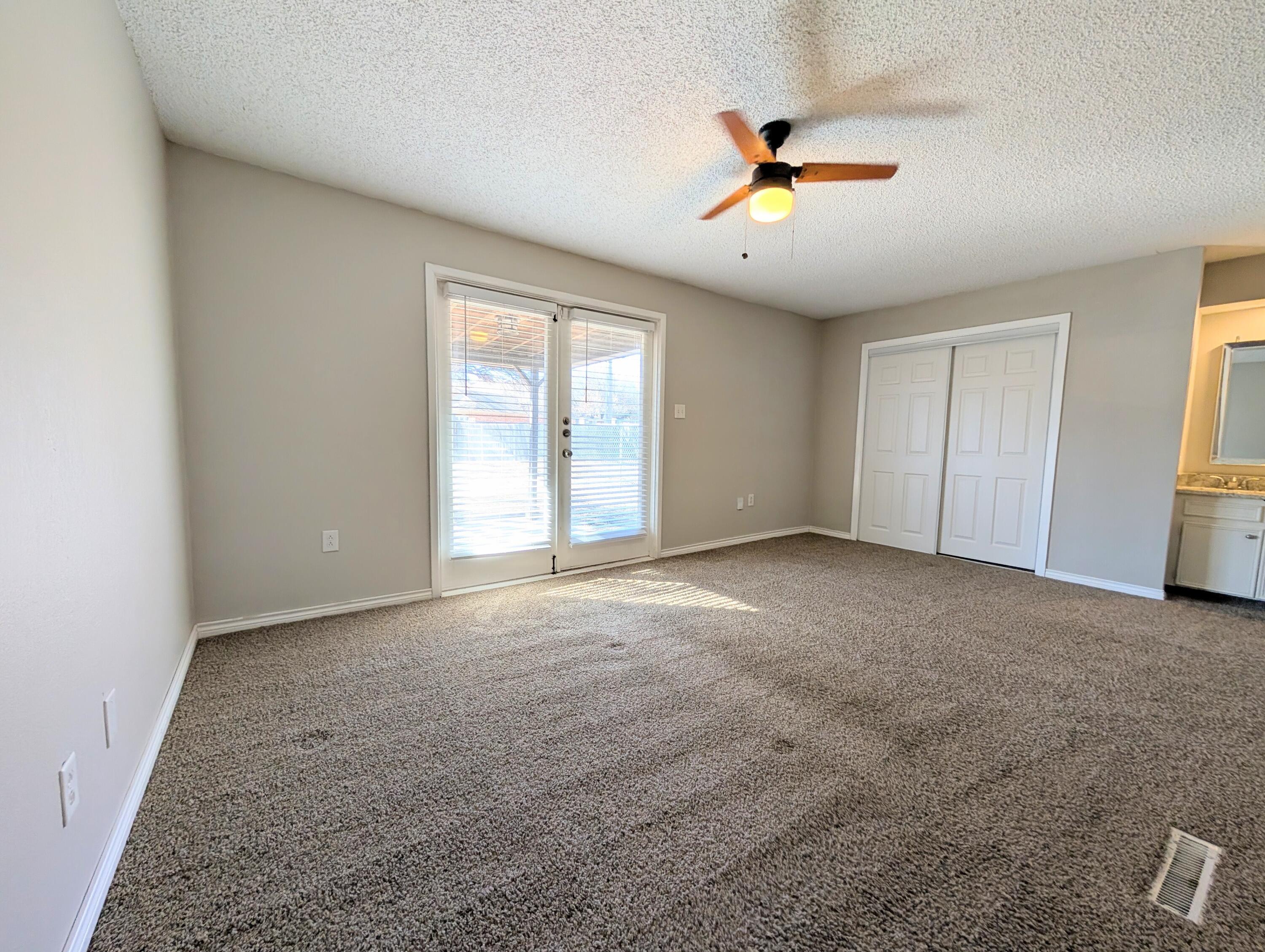 5201 18th Street, Unit A Lubbock, TX 79416 - Photo 7 of 10 a view of an empty room with a ceiling fan and window