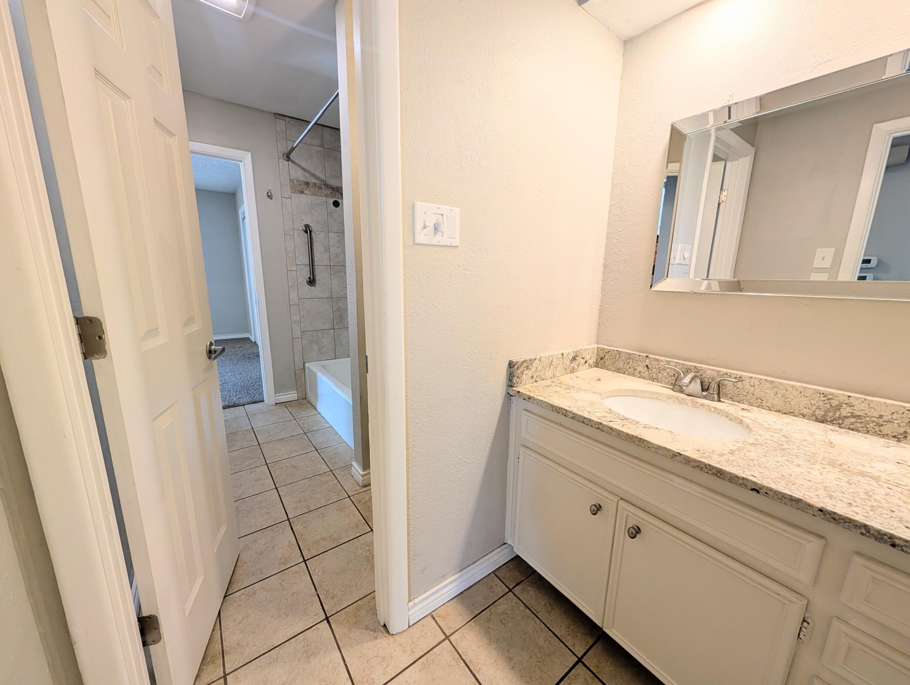 5201 18th Street, Unit A Lubbock, TX 79416 - Photo 9 of 10 a bathroom with a granite countertop sink and a mirror
