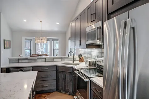 a kitchen with stainless steel appliances granite countertop a refrigerator a sink a stove and a wooden floors