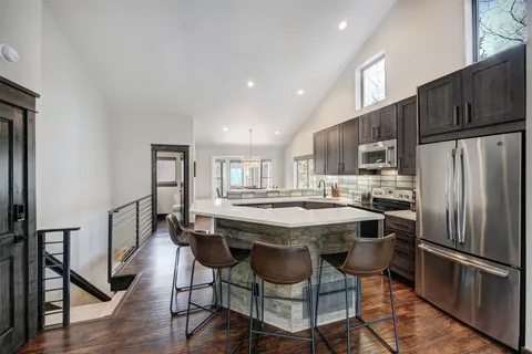 a kitchen with stainless steel appliances a dining table chairs refrigerator and microwave