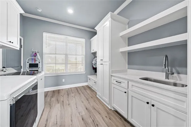 a kitchen with a sink wooden floor and white cabinets