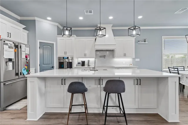 a kitchen with kitchen island granite countertop a sink a center island stainless steel appliances and cabinets
