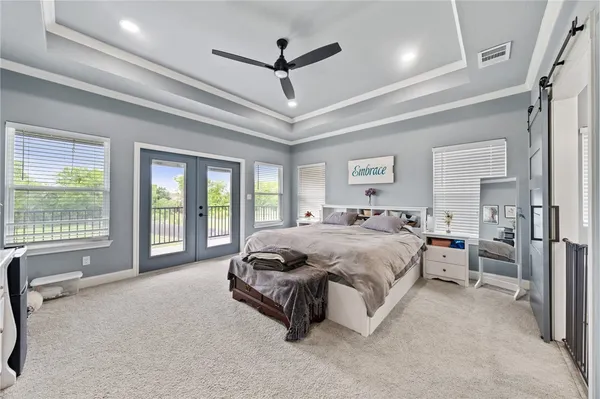 a spacious bedroom with a bed a ceiling fan and a large window