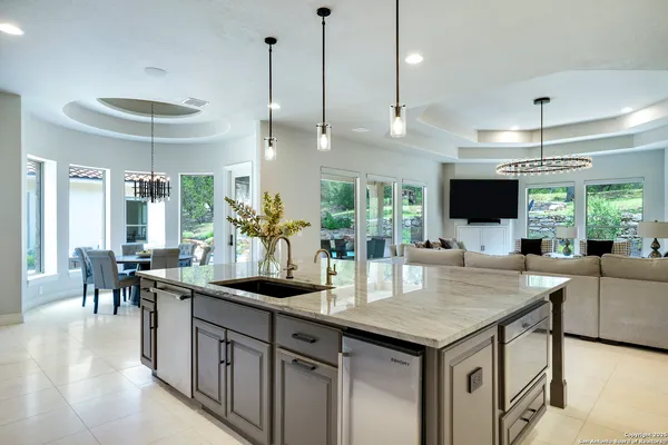 a kitchen with stainless steel appliances kitchen island granite countertop a table chairs in it and white cabinets