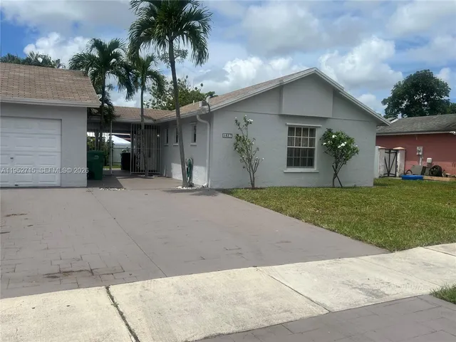 front view of a house with a yard and palm trees