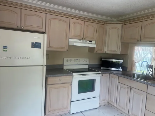 a kitchen with granite countertop white cabinets and white appliances
